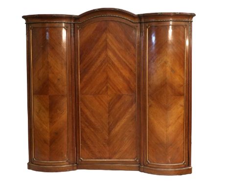 An Early 20th Century French-Style Kingwood and Parcel-Gilt Bowfront Triple-Door Wardrobe, the reeded and arched canopy above