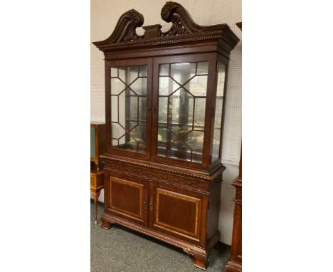 A Georgian style, reproduction, bookcase cabinet, carved scroll cresting and cornice, pair of astral-glazed doors enclosing t