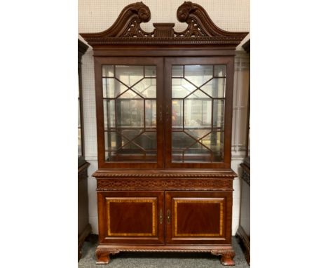 A Georgian style, reproduction, bookcase cabinet, carved scroll cresting and cornice, pair of astral-glazed doors enclosing t