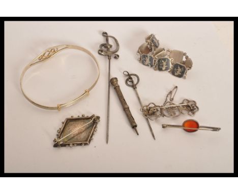 A group of sterling silver jewellery to include a Celtic knot bangle , horse shoe and riding crop brooch , red stone bar broo