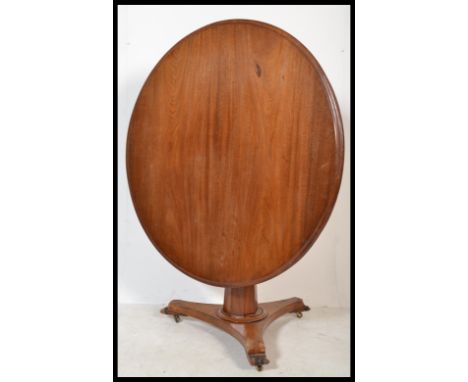 A Victorian 19th century mahogany tilt top breakfast / loo table being raised on a tripod base with tapering column and circu