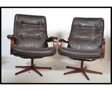 A pair of Scandinavian 20th Century retro vintage swivel easy / lounge chairs / armchairs&nbsp;having brown leather button ba