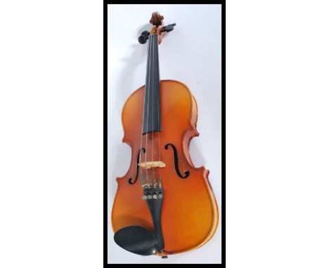 A vintage 20th century student violin with pierced hollow body and shaped neck and head. Makers label to interior.&nbsp;