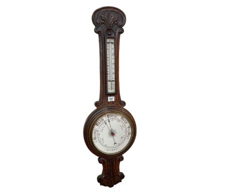Carved oak aneroid barometer with enamelled dial, 89cm.
