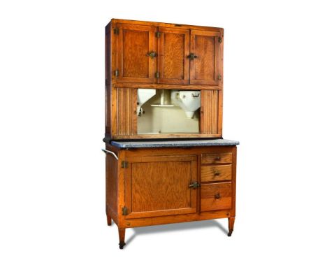 An early 20th century American oak and enamel kitchen unit by Hoosier, the three door cupboard top above a pair of tambour do