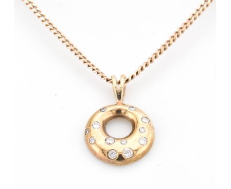 An Italian hallmarked 9ct gold and diamond pendant necklace. The 9ct yellow gold round pierced necklace pendant set with twel