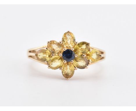 A hallmarked 9ct gold and sapphire cluster ring. The 9ct yellow gold ring set with a central round cut blue sapphire surround
