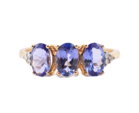 A hallmarked 9ct gold tanzanite and diamond ring. The 9ct yellow gold ring set with three oval cut tanzanite flanked to each 