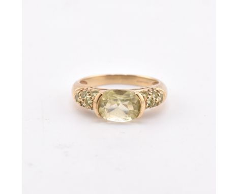 A hallmarked 9ct gold lemon citrine and peridot ring. The 9ct yellow gold ring having a half bezel set oval cut lemon citrine