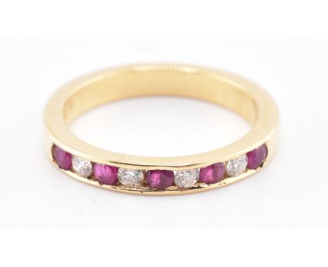 A hallmarked 18ct gold ruby and diamond ring. The 18ct yellow gold ring having five channel set round cut rubies interspersed