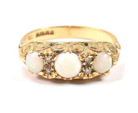 A hallmarked 18ct gold, opal and diamond three stone ring. The 18ct yellow gold ring having three round opal cabochons and fo