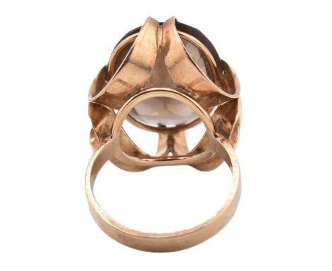 A 1970s hallmarked 9ct gold and smoky quartz cocktail ring. The ring set with a single oval cut smoky quartz set in a decorat