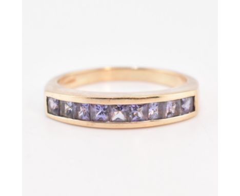 A hallmarked 9ct gold and amethyst half hoop ring. The 9ct yellow gold ring set with nine channel set princess cut amethysts 