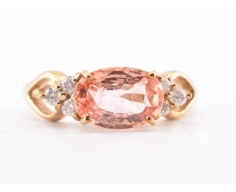 A hallmarked 9ct gold, orange sapphire and diamond ring. The 9ct gold ring set with a central east-west set oval cut orange s