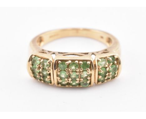 A hallmarked 9ct gold and tsavorite ring. The 9ct yellow gold ring set with twenty-one round cut tsavorite set in a pierced m