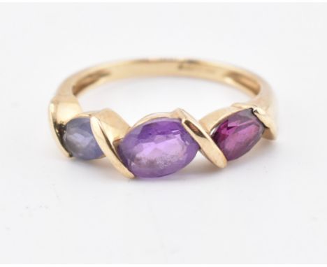A hallmarked 9ct gold amethyst, garnet and iolite three stone ring. The ring set with a single row comprised of an oval cut a