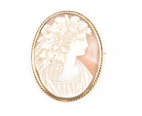 A gold cameo brooch pin. The brooch pin having an oval carved cameo depicting the profile of a young woman set in a decorativ