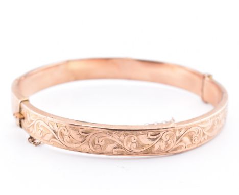 A hallmarked 9ct gold engraved hinged bangle. The 9ct rose gold bangle having a scrolling engraved decoration with hinge to p