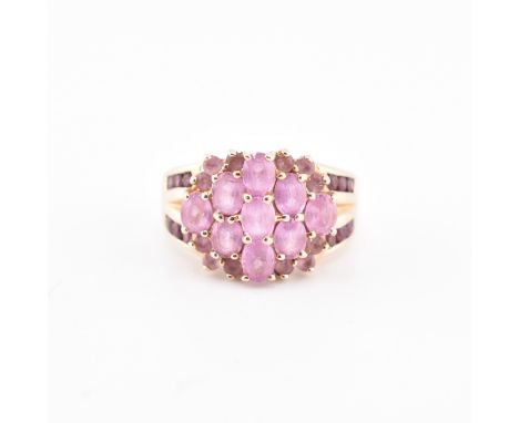 A hallmarked 9ct gold pink sapphire and garnet cluster ring. The 9ct gold cluster ring set with nine oval cut pink sapphires 