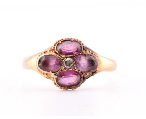 A Victorian hallmarked 15ct gold, garnet and diamond flower ring. The Victorian gold ring having a round cut diamond surround