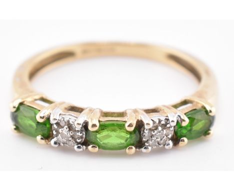 A hallmarked 9ct gold, diopside and diamond ring. The 9ct yellow gold ring set with three east-west set oval cut diopside int
