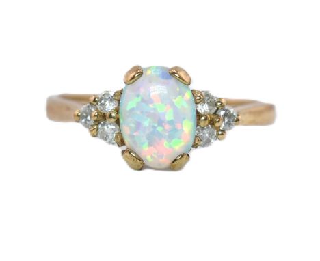 A hallmarked 9ct gold synthetic opal and diamond ring. The 9ct yellow gold ring set with an oval synthetic opal cabochon flan