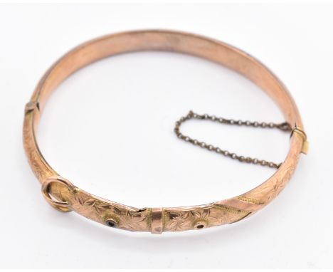 An Edwardian hallmarked 9ct gold buckle bangle. The 9ct yellow gold hinged bangle having bright cut engraved decoration with 
