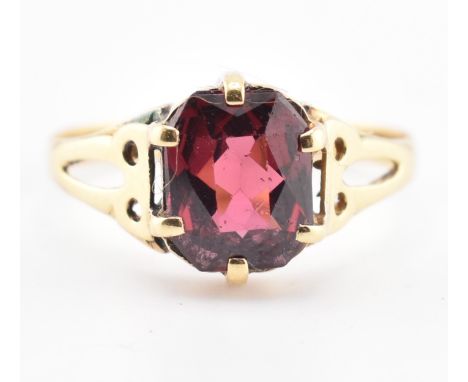An 18ct gold and garnet ring. The 18ct yellow gold ring set with a six-claw set single fancy cut garnet to pierced shoulders.