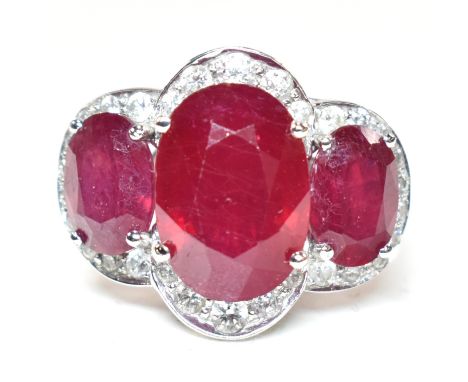 An impressive 18ct white gold three stone ruby and diamond ring. The ring set with three graduating oval cut rubies (enhanced
