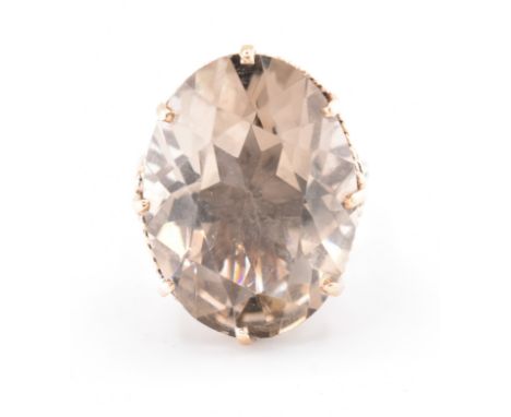 A hallmarked 9ct gold and smoky quartz cocktail ring. The 9ct yellow gold ring having a single oval cut smoky quartz set in a