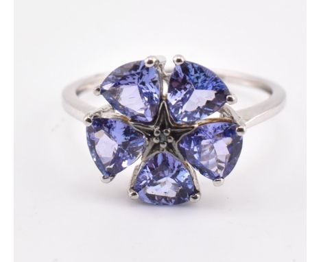 A hallmarked 9ct white gold tanzanite and blue diamond flower ring. The 9ct white gold ring set with a central round cut blue