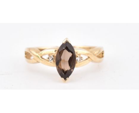 A hallmarked 9ct gold smoky quartz and white topaz ring. The 9ct yellow gold ring set with a central marquise cut smoky quart