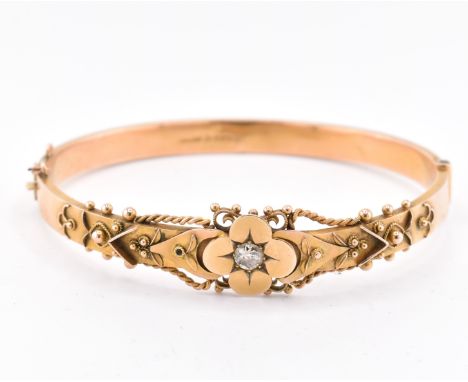 An early 20th century hallmarked 9ct gold and diamond hinged bangle. The bangle set with a central old cut diamond in a flora