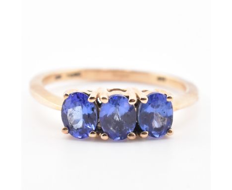 A hallmarked 9ct gold and tanzanite three stone ring. The ring set with three four-prong set oval cut tanzanite to tapered sh
