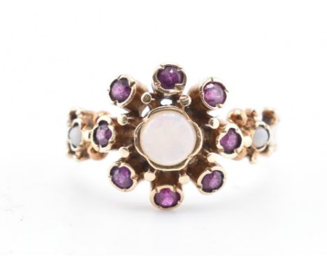 A 9ct gold opal and pink stone ring. The 9ct yellow gold ring set with a central round opal cabochon surrounded by eight beze