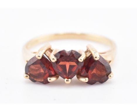 A hallmarked 9ct gold Mozambique garnet three stone ring. The 9ct yellow gold ring set with three heart-shape Mozambique garn