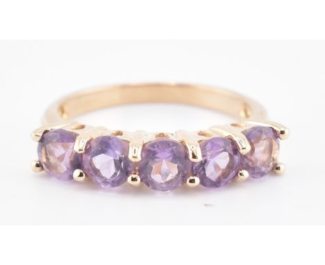 A hallmarked 9ct gold and amethyst five stone ring. The 9ct yellow gold ring having a single row of five round cut amethysts 