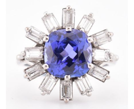 An 18ct white gold tanzanite and diamond cluster ring. The 18ct white gold ring set with a central cushion cut tanzanite (9mm