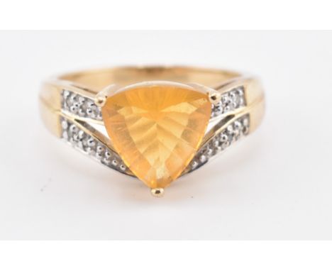 A hallmarked 9ct gold, Brazilian fire opal, and diamond ring. The 9ct yellow ring set with a central trilliant cut Brazilian 