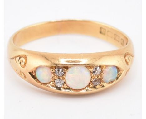 A Victorian hallmarked 18ct gold opal and diamond ring. The ring set with three round opal cabochons highlighted with four ol