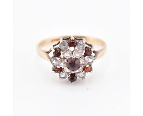 A hallmarked 9ct gold and gem set cluster ring. The 9ct yellow gold ring set with a cluster of round cut red stones and round