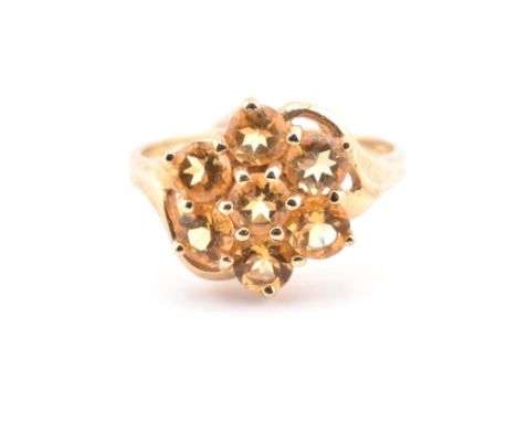 A hallmarked 9ct gold and citrine cluster ring. The 9ct yellow gold ring set with a six claw set round cut citrine surrounded