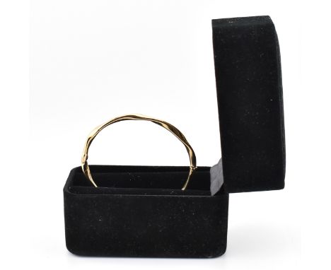 A hallmarked 9ct gold hinged bangle cased. The 9ct yellow gold bangle having a twisted design with hinge to box clasp. Hallma