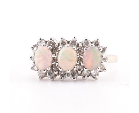 A hallmarked 9ct gold opal and diamond three stone ring. The yellow gold ring set with three claw set oval opal cabochons sur