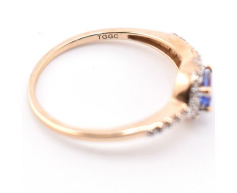 A hallmarked 9ct gold tanzanite and white stone ring. The 9ct yellow gold ring having an east-west set fancy cut tanzanite su