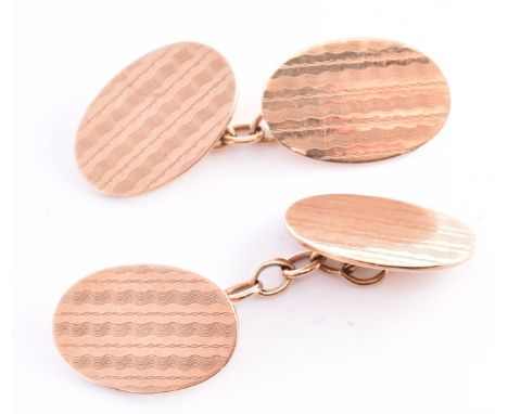 A pair of hallmarked 9ct gold cufflinks. The 9ct yellow gold cufflinks having oval heads with engine turned repeating pattern