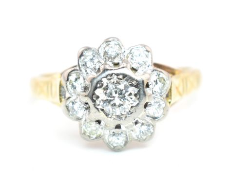 A hallmarked 18 ct gold and diamond flower cluster ring. The ring set with a central round brilliant cut diamond framed by te