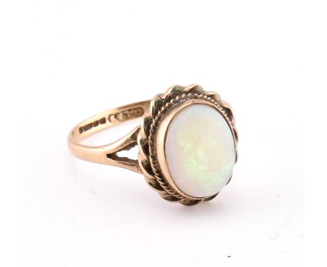 A hallmarked 9ct gold and opal ring. The 9ct yellow gold ring set with a single bezel set oval opal cabochon set in a decorat