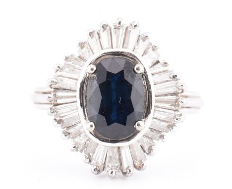 An 18ct white gold sapphire and diamond ballerina cluster ring. The 18ct white gold ring set with a central four claw set ova