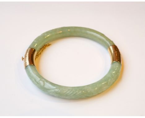 CHINESE CARVED JADE BANGLE
with entwined foliate carving to the bangle and with fourteen carat gold mounts